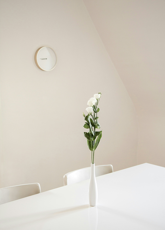 Vase blanc avec bouquet minimaliste sur table dans un intérieur épuré