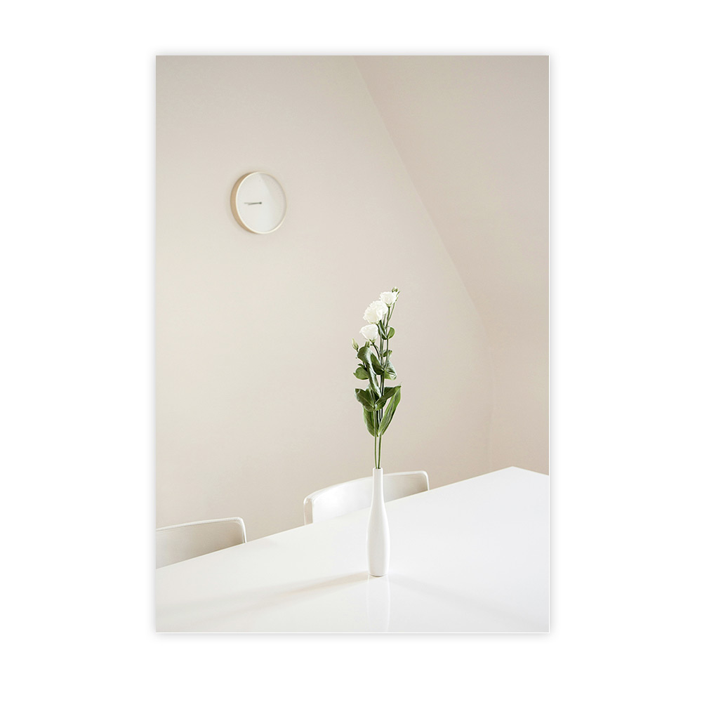 Vase blanc avec bouquet minimaliste sur table dans un intérieur épuré